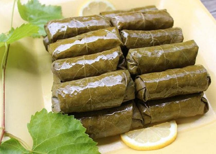 Boil grape leaves until the leaves are soft and change color, then drain and set aside to cool.  Soak the rice in hot water for 30-120 minutes, then drain it from the water.  In a large, deep bowl, combine rice, raw minced meat, parsley and tomatoes.  Add salt and spices to the rice mixture to taste.  Start by stuffing the grape leaves with the rice filling, with the rough side of the leaf facing the filling.  Make sure the grape leaves are wrapped tightly, and then start stacking them in a deep saucepan after placing the potato slices, tomatoes, and onions in the bottom of the pot.  Put a few slices of tomato on the face.  Submerge the grape leaves in meat broth or chicken broth mixed with tomato puree or tomato juice, and put the cooker on gas over high heat.  Reduce the temperature when the broth begins to boil, cover the pot, and it is possible to place an inverted dish on the stuffed grape leaves before covering the pot with the lid to ensure that the stuffed fingers remain firm.  Wait 1-2 hours until the stuffed grape leaves are completely cooked, but you can add water every now and then whenever you feel the broth is starting to dry out from the grape leaves.